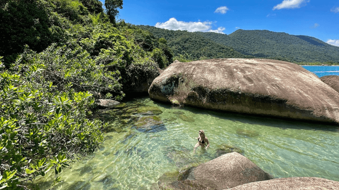 Explore the lush Atlantic Forest on a trail leading to pristine beaches and natural pools in Trindade.